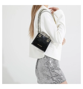 Detail view of black patent leather crossbody bag with gold lettering and chain strap