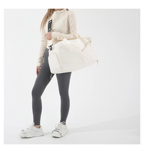 White minimalist waterproof nylon duffle bag with adjustable padded shoulder strap on model