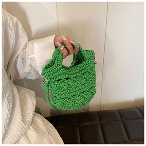 Close-up of the grass green hand-woven knit fabric texture on a trendy shoulder bag