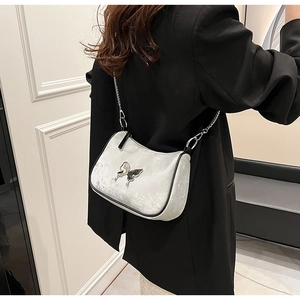 Détail du sac demi-lune en velours argenté avec papillon en métal et chaîne élégante