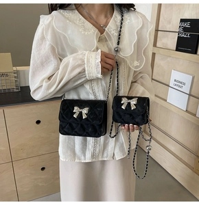 Detailed view of black quilted mini bags with silver metal bows and chain straps