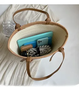 Detailed interior of a spacious straw tote bag showing brown leather handles and ample room