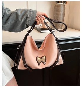 Detail of pink PU leather bag with golden butterfly charm and adjustable brown strap