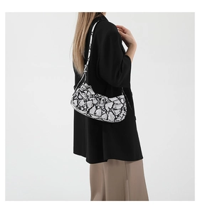 Detail shot of a trendy snake-print faux leather hobo shoulder bag worn by a model