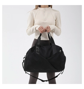 Detail of a black nylon crossbody sports bag with a diagonal zipper pocket and handles