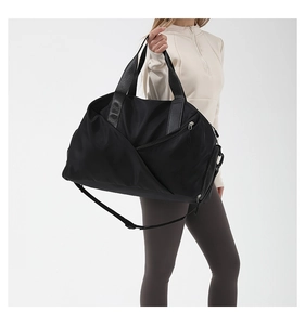 Detail of a large black nylon fitness bag featuring a zipper pocket and adjustable strap