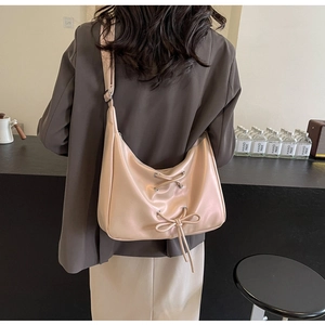 Detail view of cream PU leather hobo bag with eyelet lace-up bow and retro metallic studs
