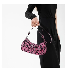 Detailed view of pink snake pattern crossbody bag with metal ring buckle on model