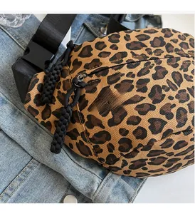 Detail view of leopard print canvas chest bag with woven zipper pull on denim jacket