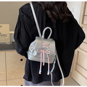 Detail of silver metallic mini backpack with pink lace-up ribbon and beaded drawstring