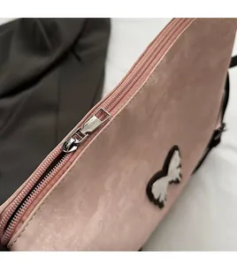 Detailed close-up of smooth silver metal zipper and butterfly charm on pink PU bag