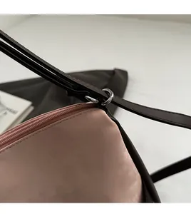 Detail of pink faux suede bag with brown leather trim and precision stitching