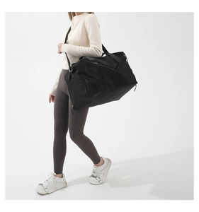 Model showing large black sports duffle bag with side shoe compartment and shoulder strap