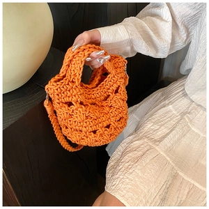 Detail of bright orange hand-knitted crossbody bag with unique geometric hollow textures