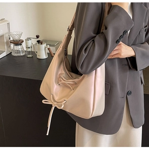 Detail of minimalist beige PU leather shoulder bag with drawstring bow and metal eyelets