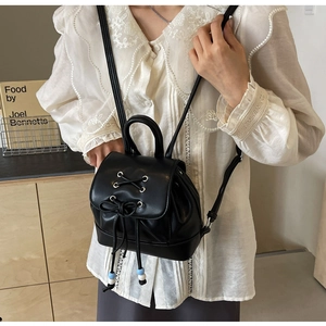 Detail of black mini backpack with ribbon bow and decorative blue-white beads