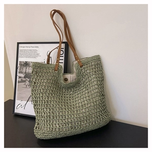 Green woven knit tote bag with brown leather straps and beige fabric lining