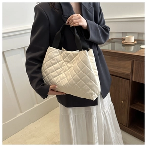 Détail du sac cabas blanc matelassé avec anses noires porté par un mannequin chic