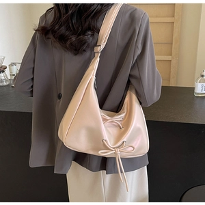 Detail of a light pink half-moon PU leather hobo bag with a stylish bow decoration