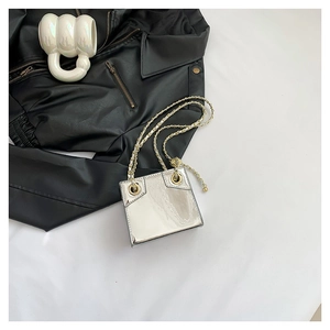 Silver mirror PU leather mini crossbody bag with golden chain strap on a black jacket