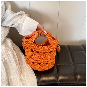 Detail of handmade crochet knit handbag in bright orange with intricate hollow textures