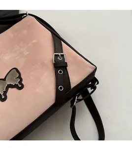 Detail of pink faux suede crossbody bag with silver butterfly hardware and brown strap