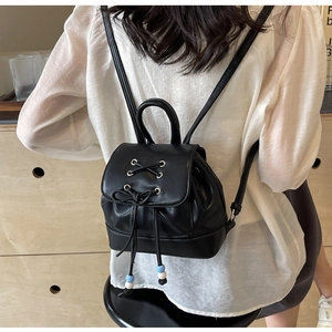 Close-up of black PU leather mini backpack with ribbon lacing details and drawstring closure