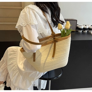 Detail view of woven straw tote bag with brown leather straps and floral accents