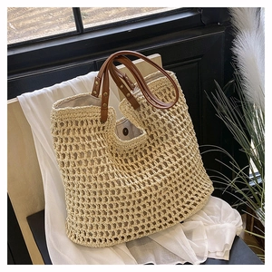 Minimalist woven straw tote bag with brown leather handles and gold rivet accents