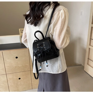 Detailed shot of black mini PU leather backpack with lace-up flap and beaded charm