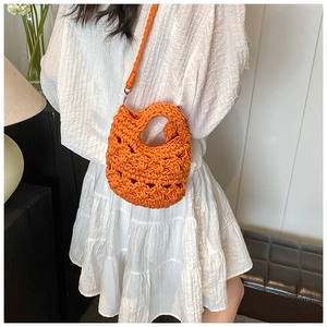 Detail of an orange hand-woven crossbody bag styled with a white summer dress