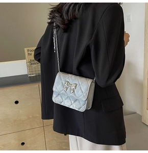 Silver quilted PU leather crossbody bag featuring a metal bow clasp and elegant chain strap