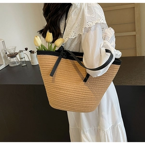 Detail of large woven straw tote bag with black trim and handles for summer beach use