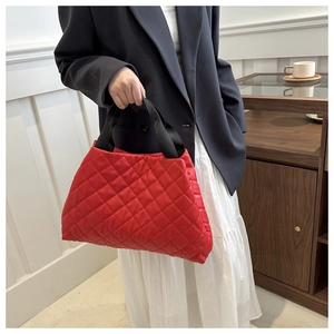 Détail d'un sac à main matelassé rouge avec poignées en sangle noire en décor intérieur