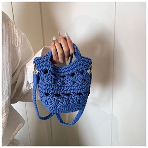 Close-up of blue hand-woven knit handbag featuring thick crochet texture and metal hooks