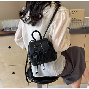 Detail of black PU leather mini backpack with ribbon bow and decorative blue beads