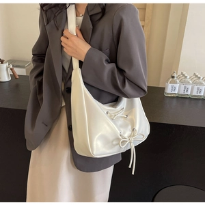 Detail view of white PU leather hobo bag with drawstring bow and wide strap on model