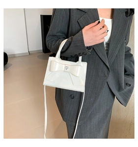 Détail du sac en cuir verni blanc avec grand nœud et fermoir coeur en métal argenté