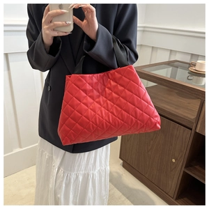 Détail d'un sac cabas matelassé rouge avec texture moelleuse et anses en nylon noir