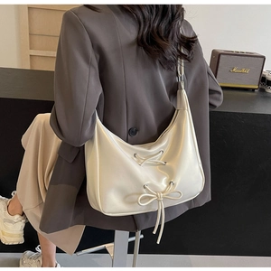 Detail of cream white PU leather hobo bag featuring lace-up bow and silver eyelets