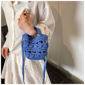 Detail of blue crochet knit crossbody bag worn over a white dress for a stylish spring look