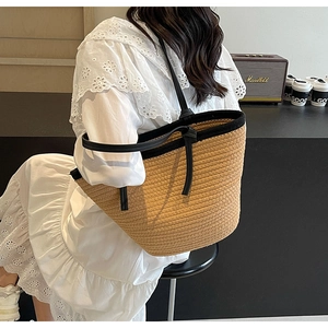 Detail of hand-woven straw tote bag with black leather straps and premium piping trim