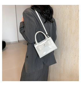 Détail du sac à main en cuir verni blanc avec nœud et boucle cœur sur un mannequin