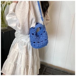 Detail view of the blue hand-woven knitted crossbody bag with hollow texture and thick strap