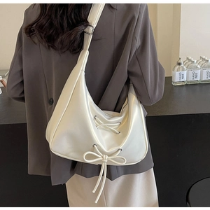 Detail view of white PU leather crossbody bag featuring adjustable straps and bow design