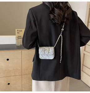 Silver mini crossbody bag with quilted pattern and metal bow detail on black blazer