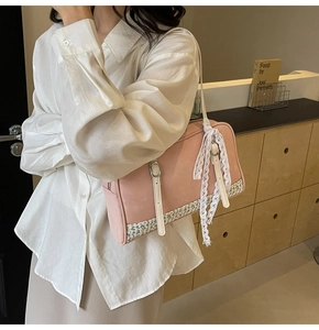 Close-up of pink PU leather handbag with floral patchwork and white lace bow detail
