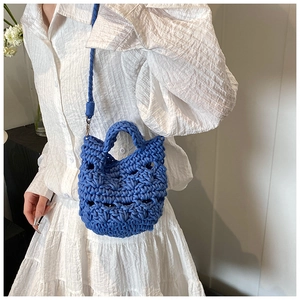 Detail of blue crochet knit crossbody bag with hollow weave texture on white dress