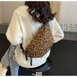 Detail showing leopard print canvas crossbody bag with dual zippers and woven puller cords