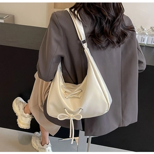 Chic cream PU leather half-moon bag featuring decorative cross-lacing and bow detail